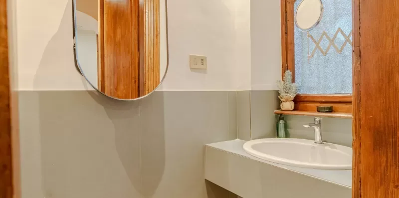 Un lavabo y un espejo están junto a una ventana esmerilada.