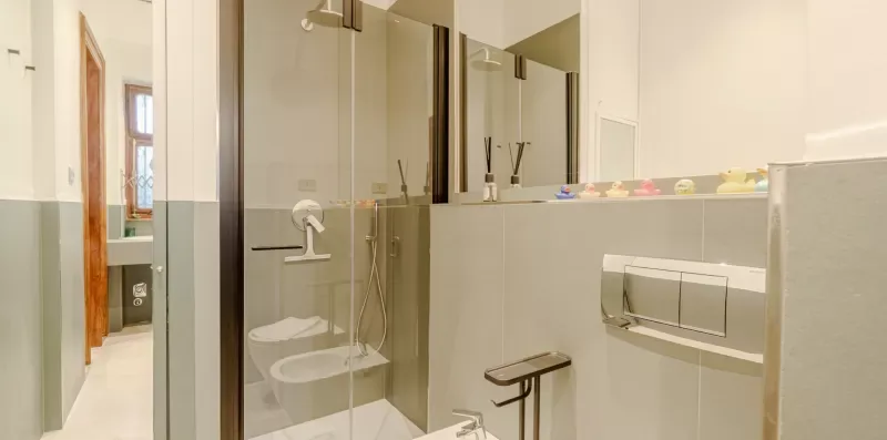 Un baño con ducha de vidrio y lavabo montado en la pared.