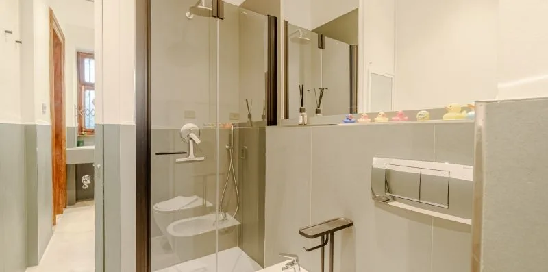 Un baño con una ducha de vidrio y un inodoro suspendido.
