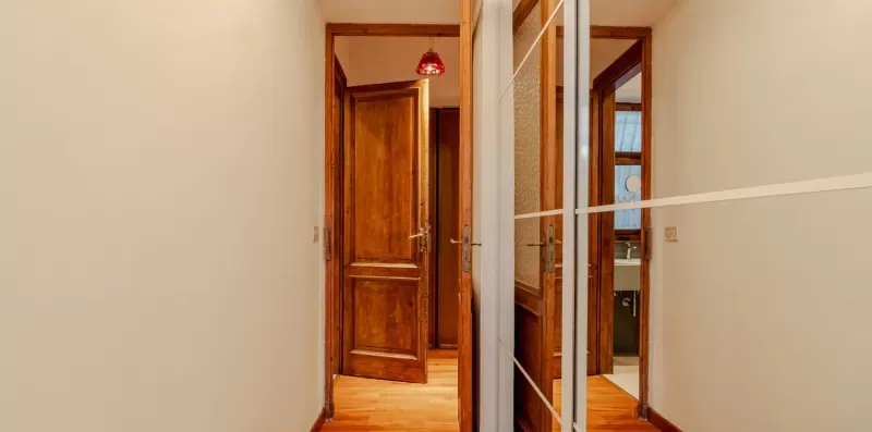 Un pasillo con puertas de madera y un armario con espejo.