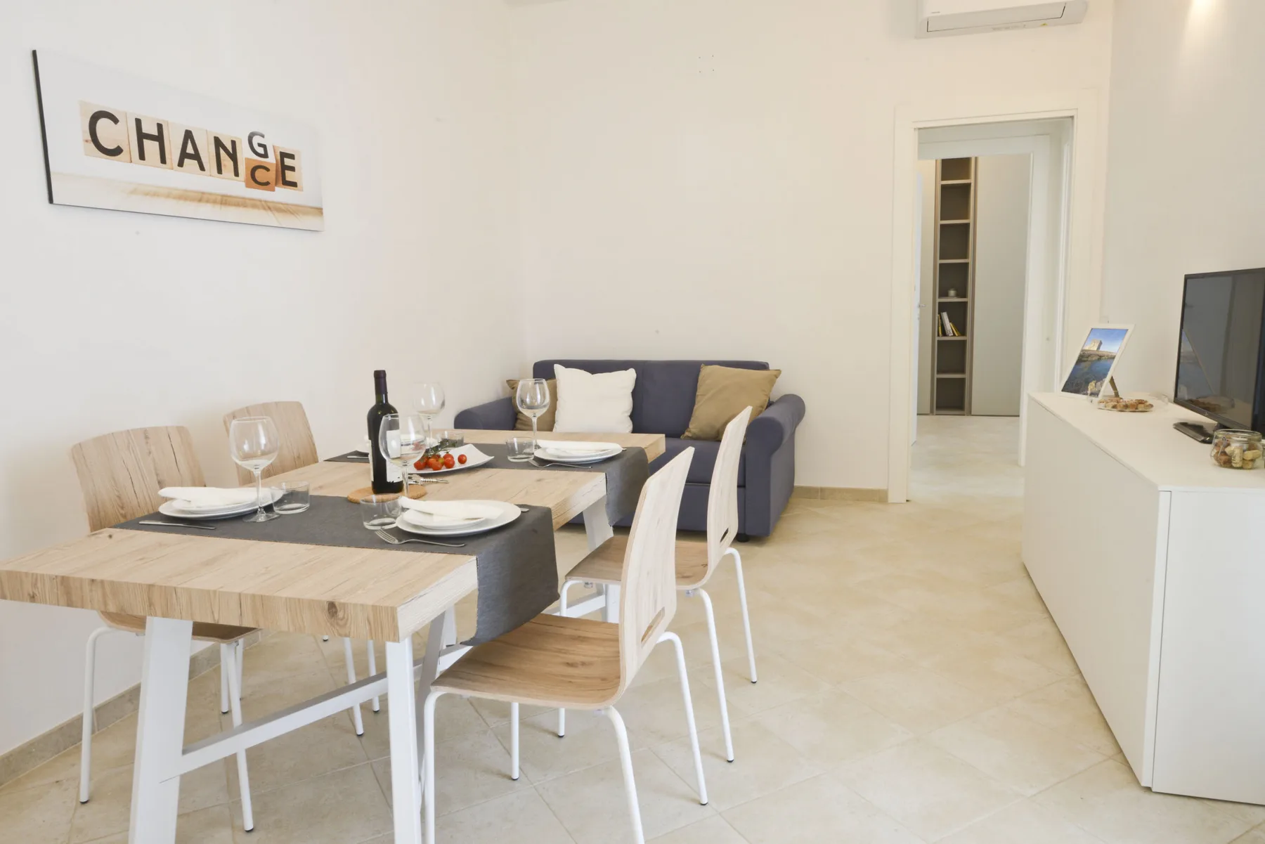 A bright dining area with a set table and a small seating area behind it.