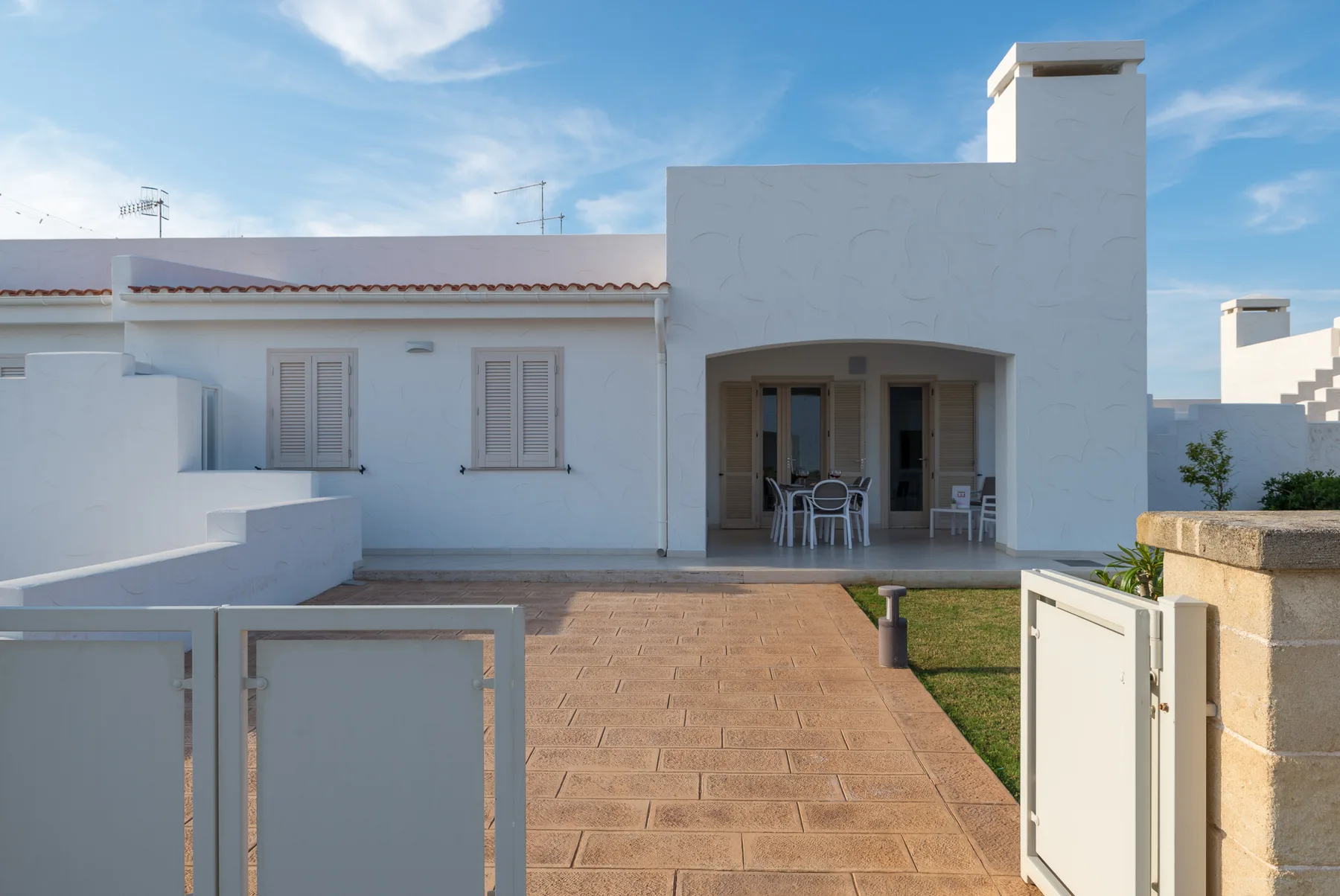 A white building opens onto a paved patio with outdoor seating.
