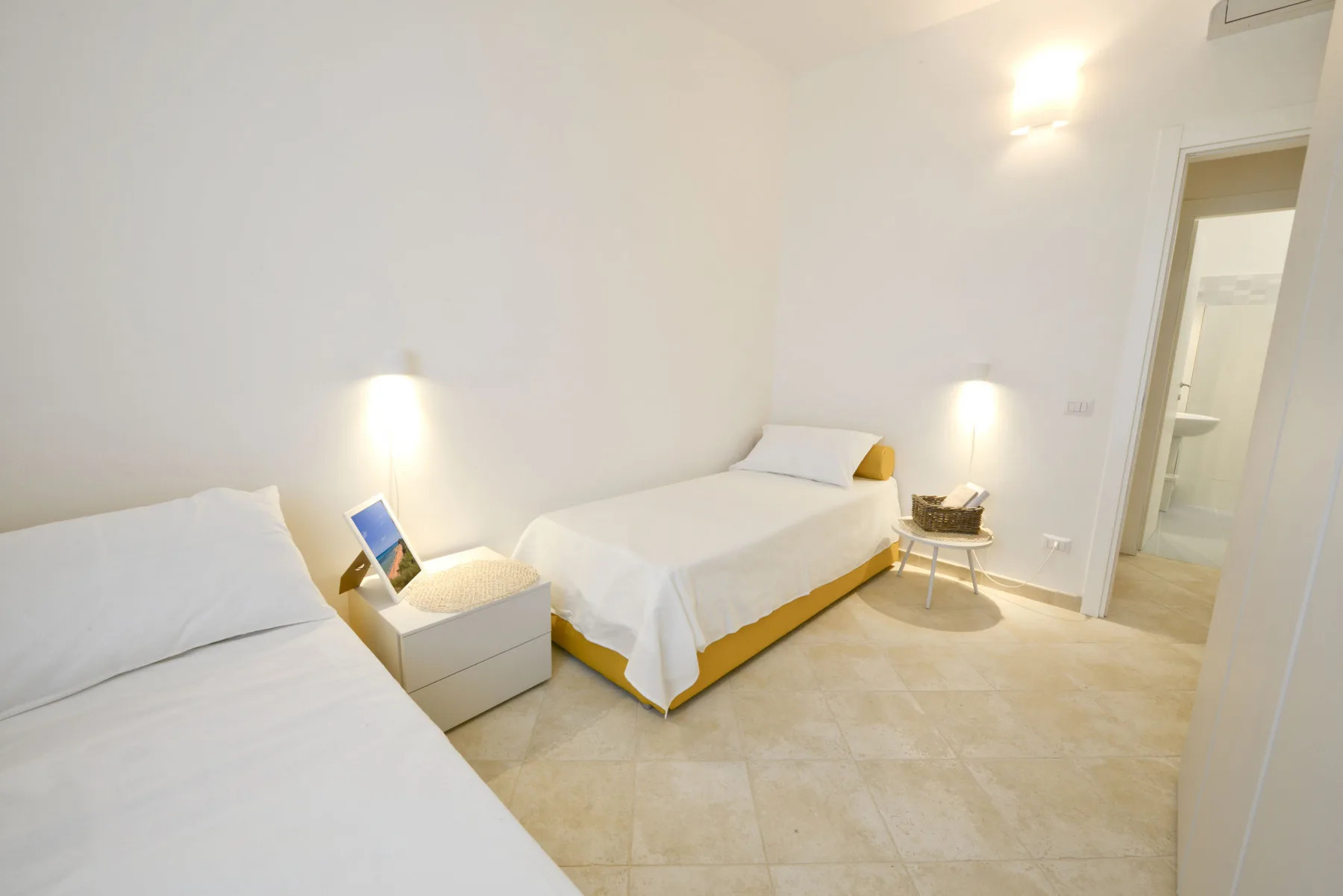 A bright bedroom with two beds and a small table between them.
