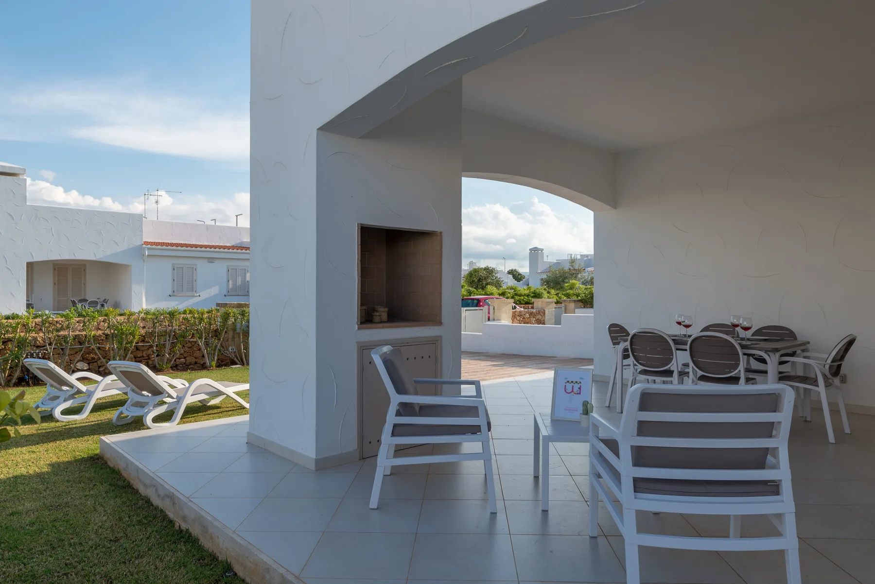 A covered outdoor patio with seating and a dining table overlooks a garden.