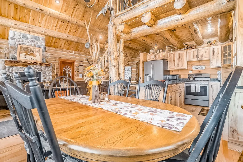 Un comedor rústico con una mesa larga de madera y la cocina al fondo.