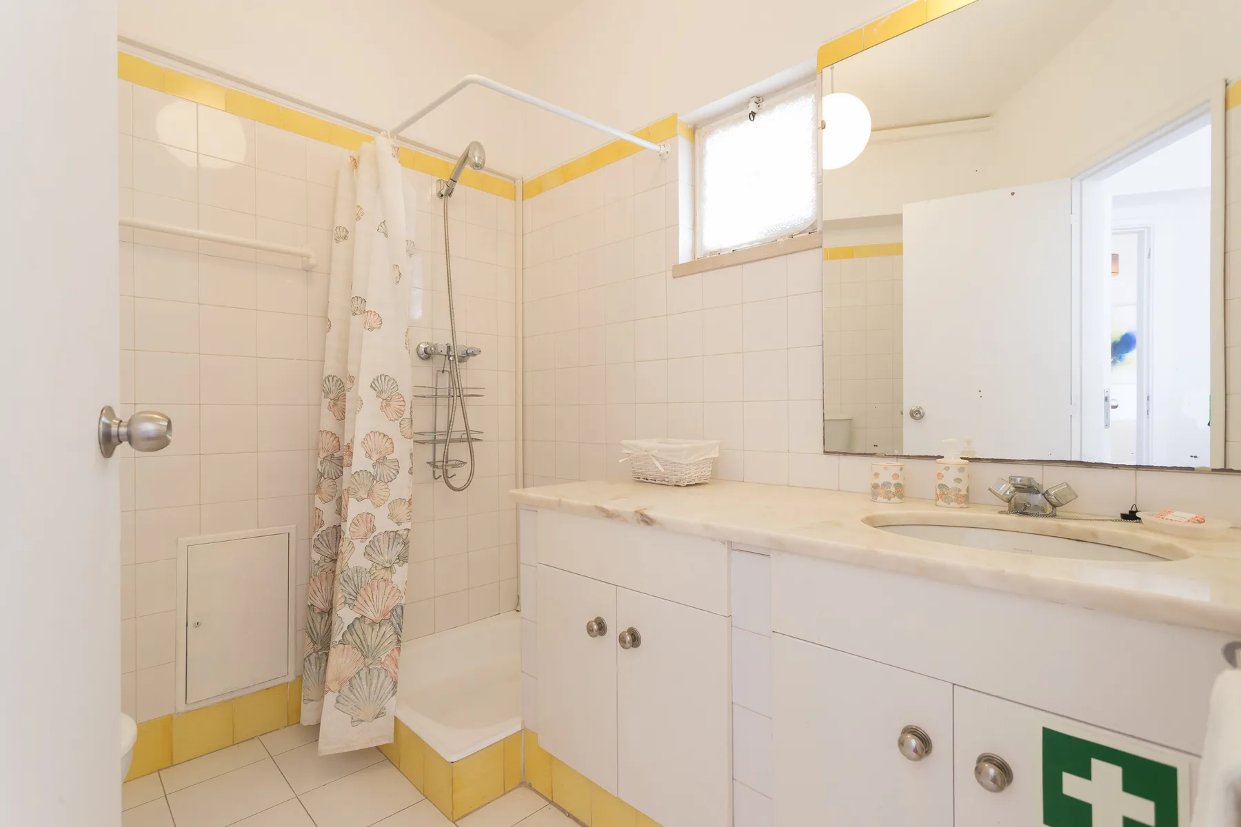 Un baño alicatado con ducha y un largo mueble de lavabo.