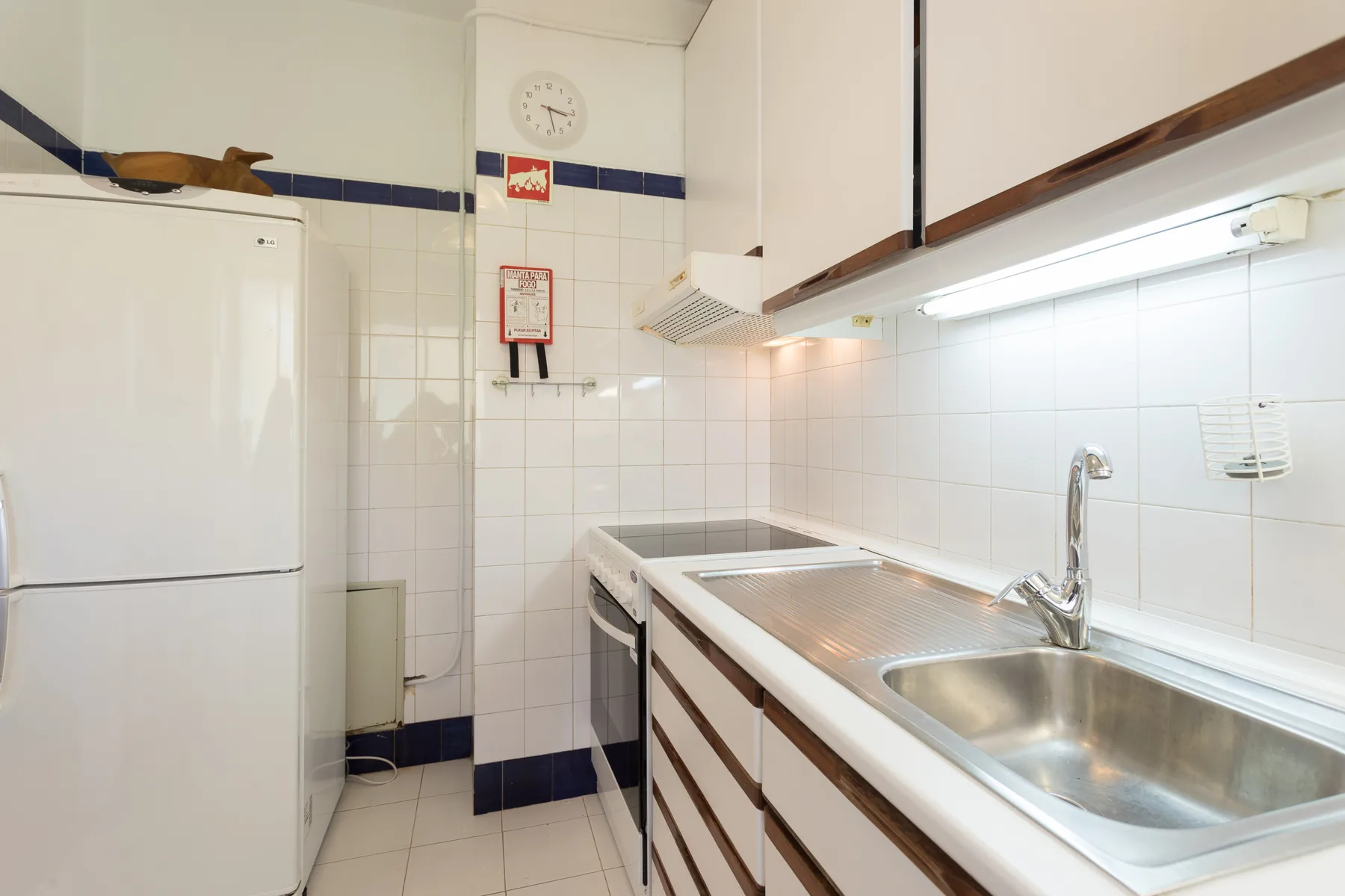 Una cocina con azulejos, refrigerador, encimera y fregadero.