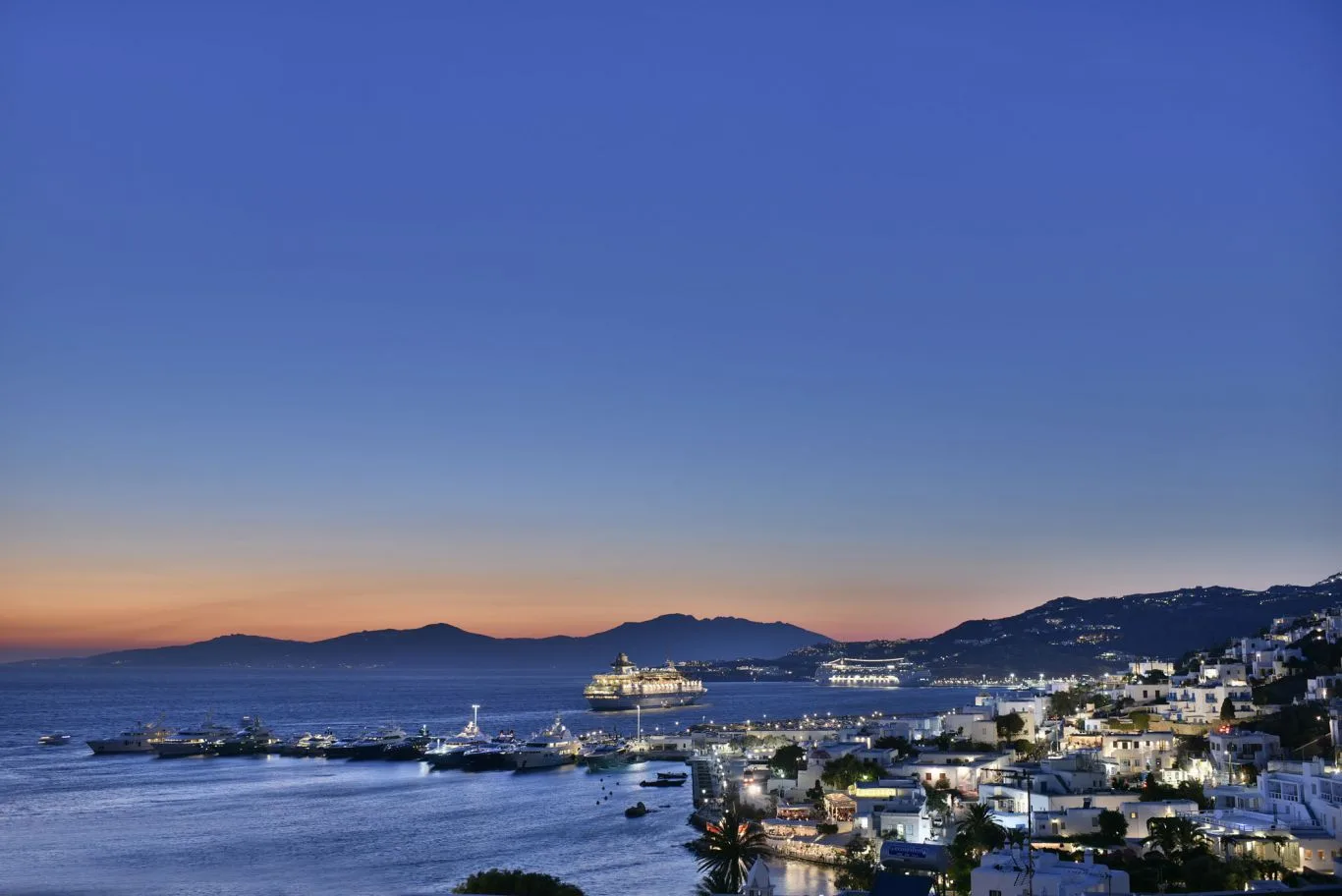 Coastal town and harbor at dusk, with boats on the water.