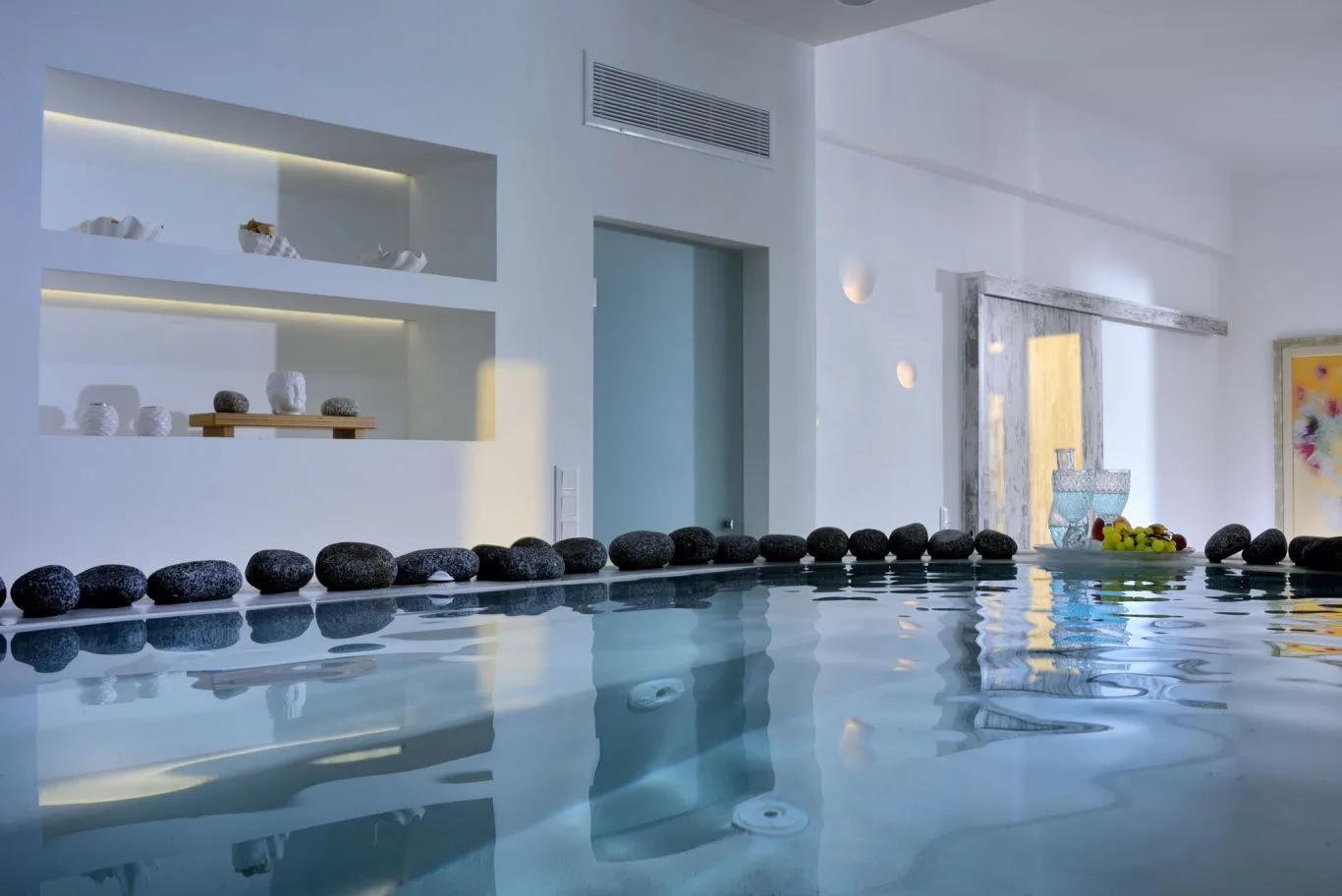 An indoor pool with decorative stones lining the edge.