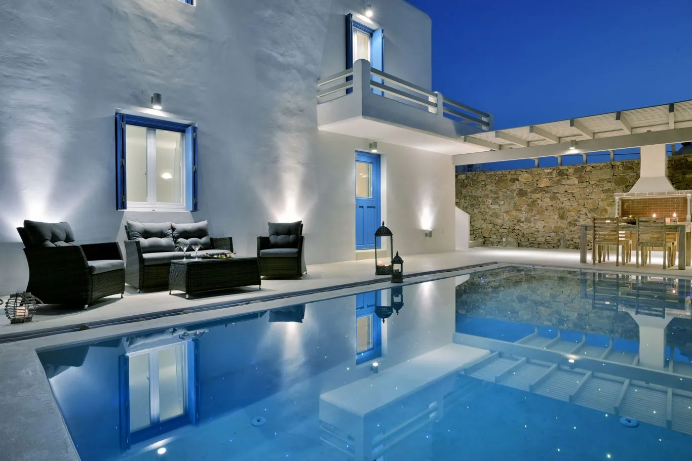 A pool beside a white building, with outdoor seating along the water.