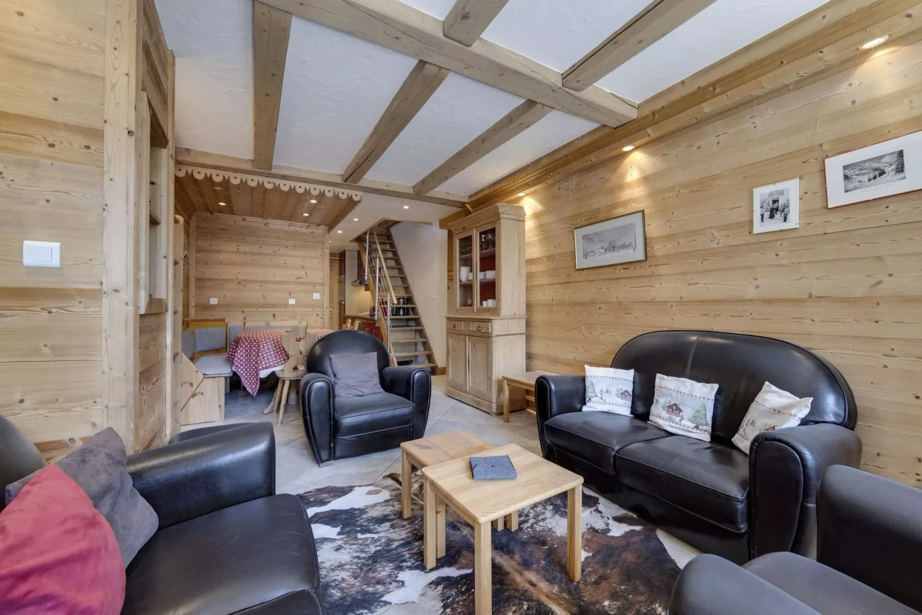 A wood-paneled living room with dark seating, a coffee table, and exposed ceiling beams.