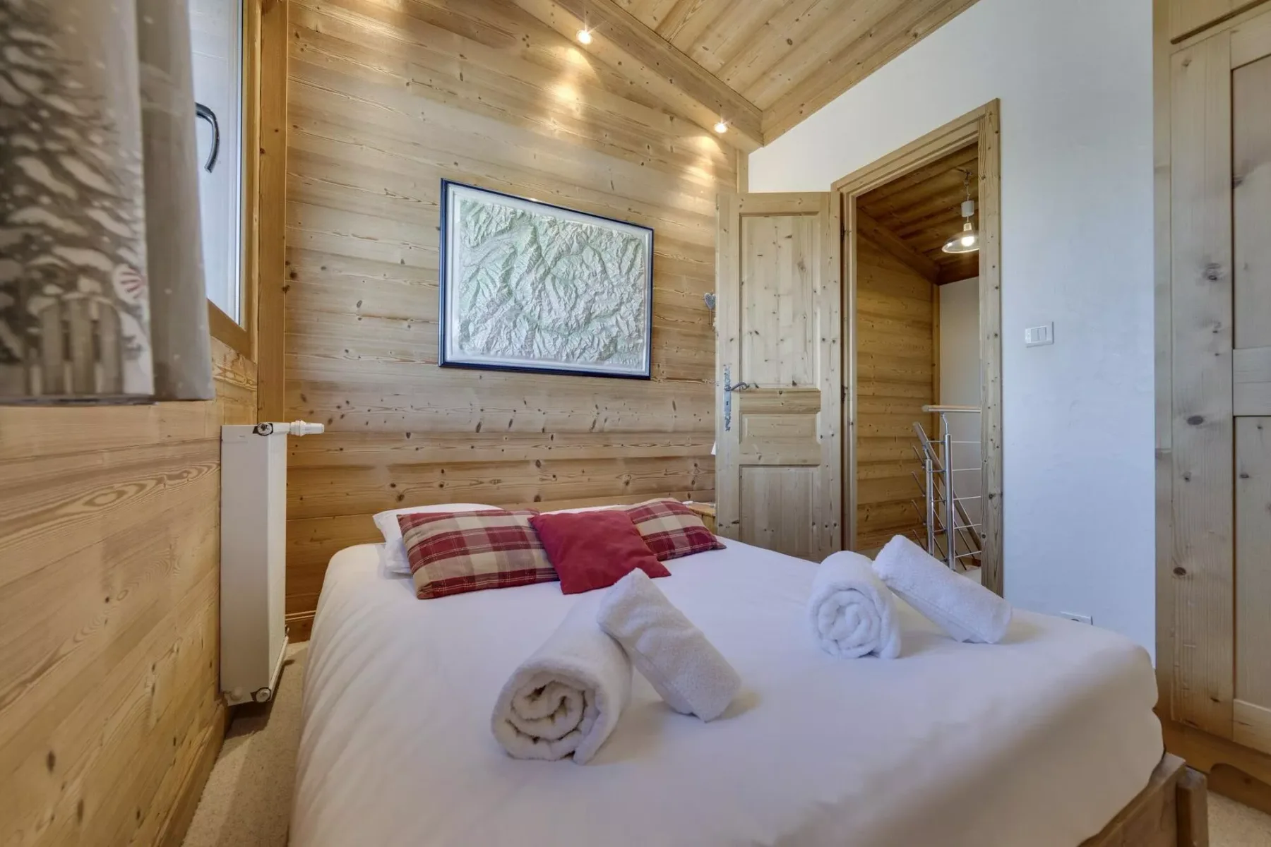 A bedroom with a bed, folded towels, and wood-paneled walls.