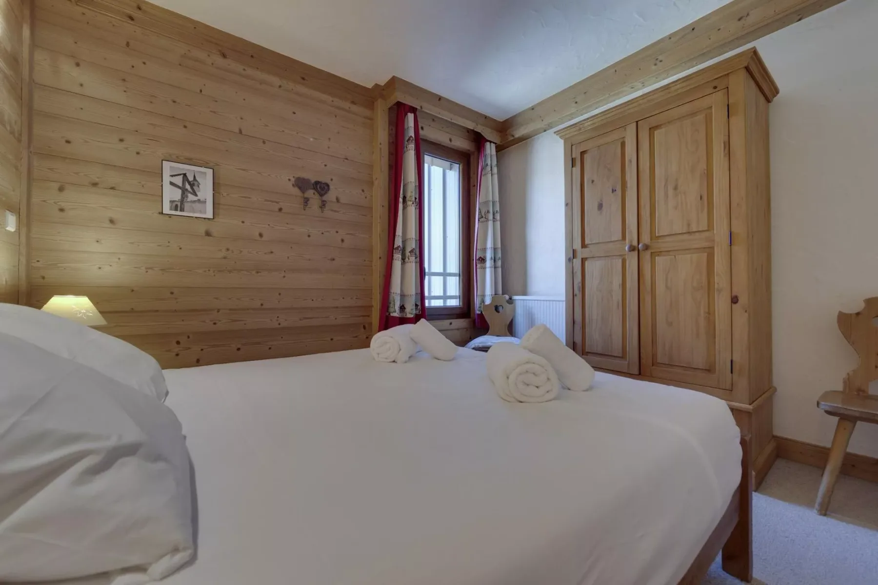 A bedroom with a large bed, wooden walls, and a built-in wardrobe.