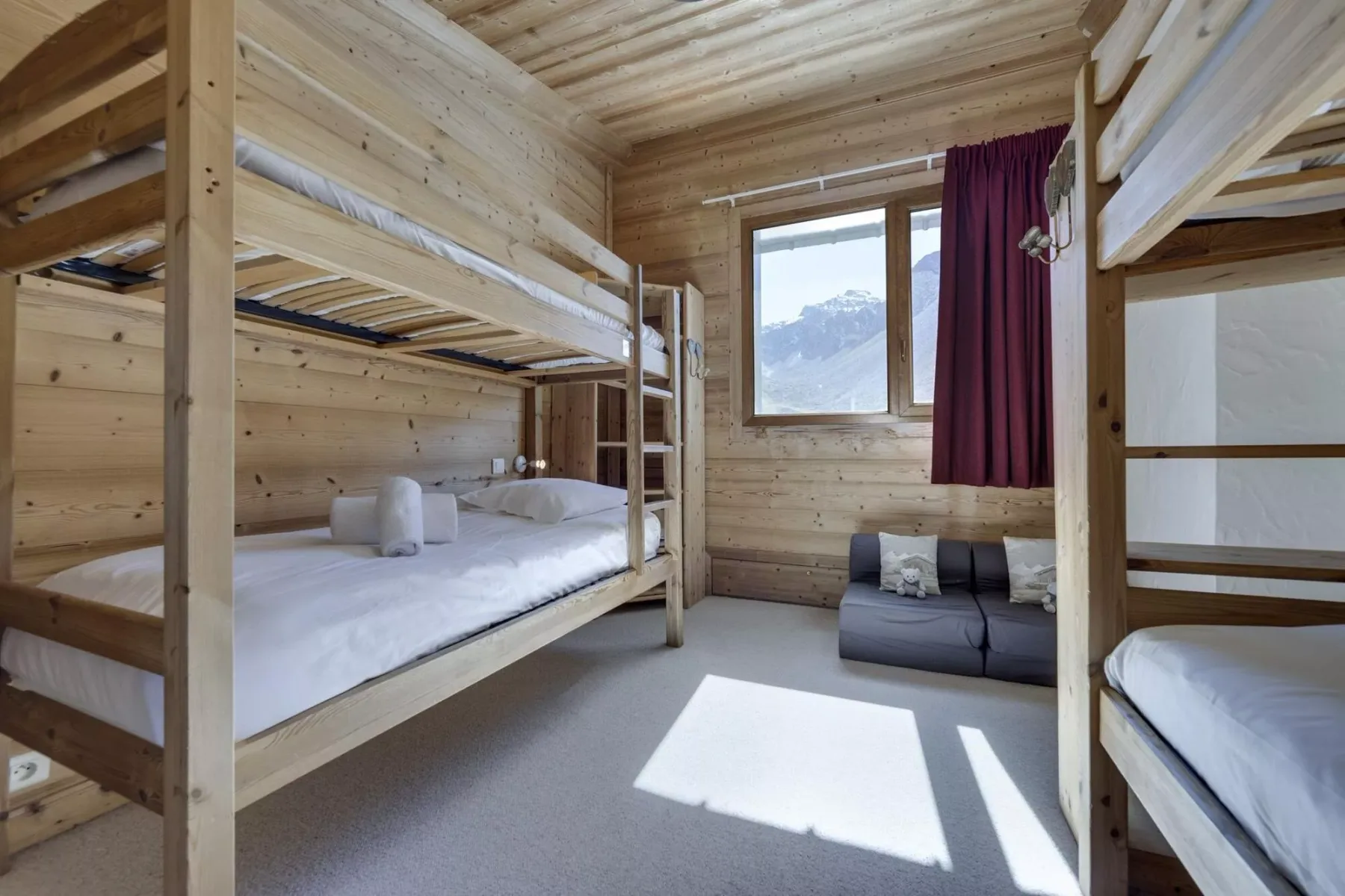 A wood-paneled bedroom with bunk beds and a window overlooking a mountain.