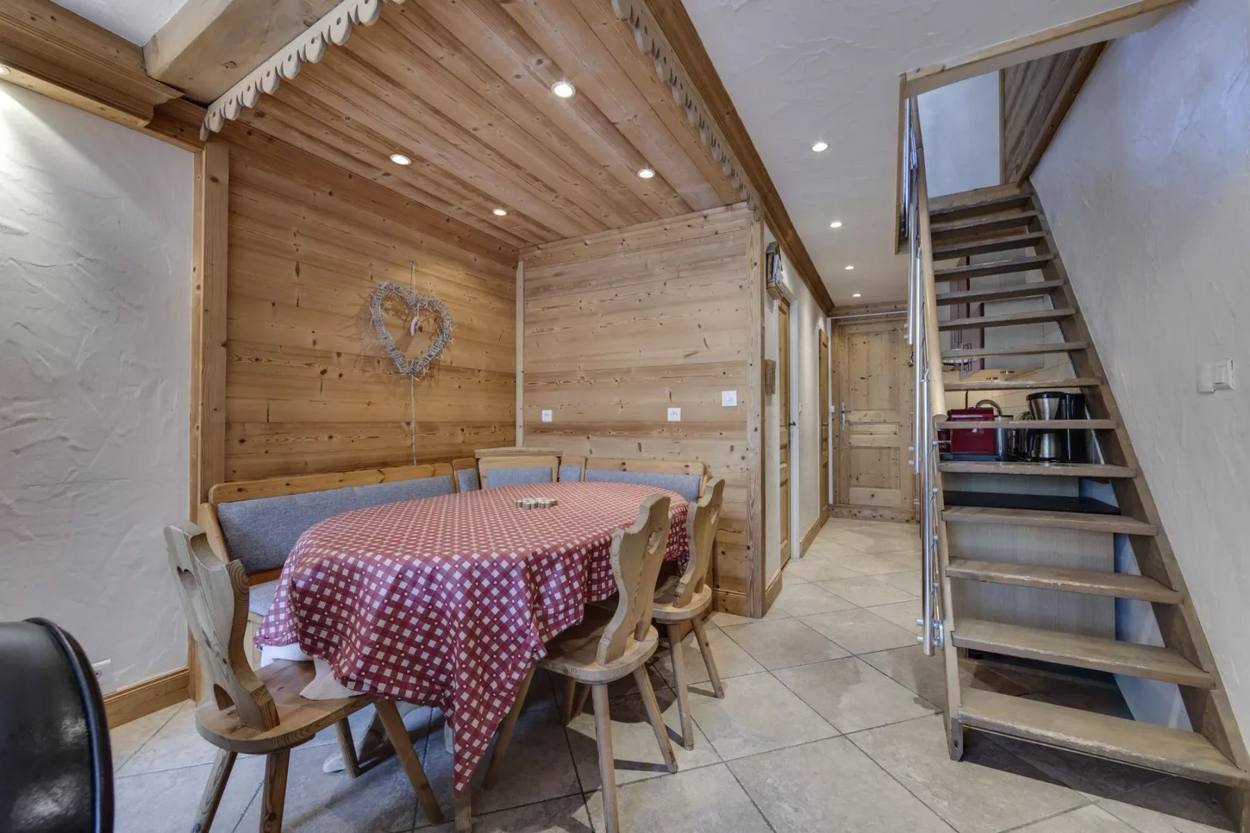 A rustic dining area with a table and wooden staircase.