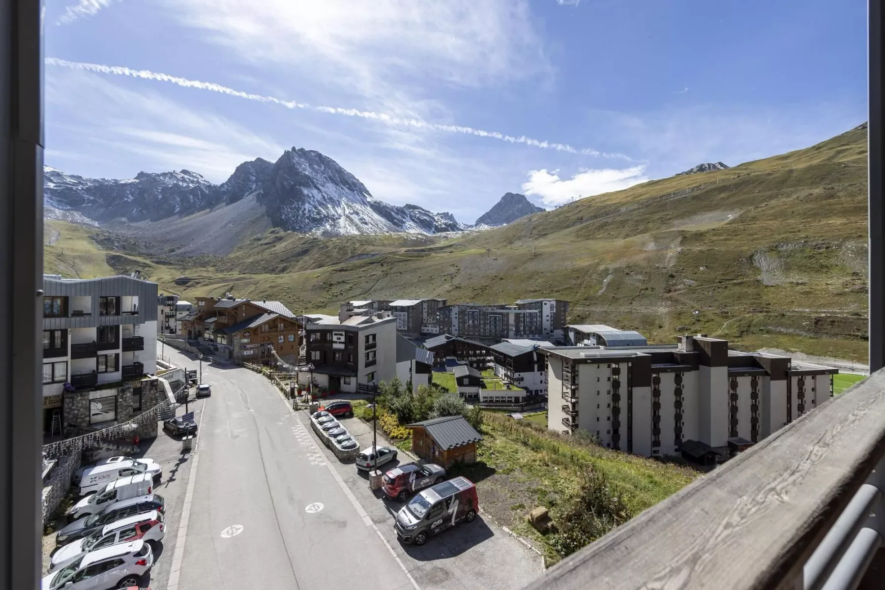 A mountain village with apartment buildings and a road below the surrounding peaks.