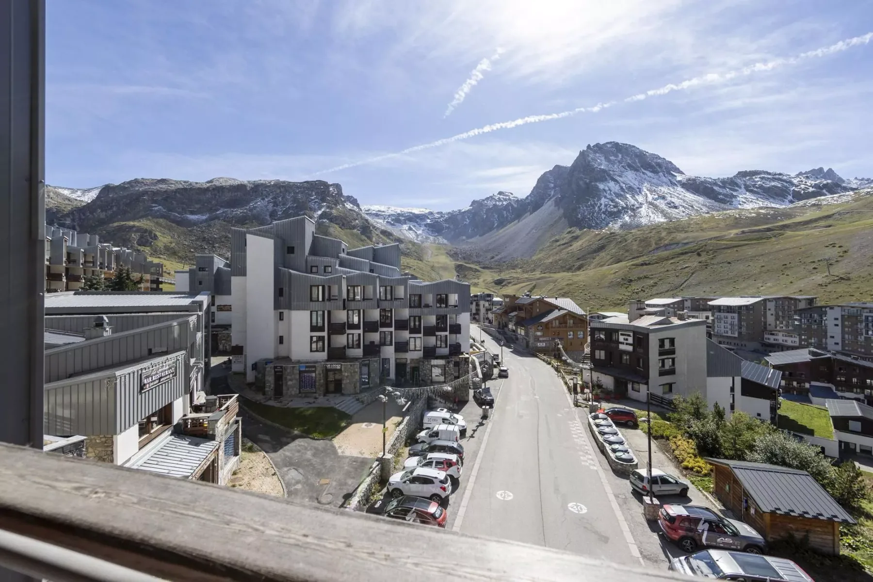 Mountain village buildings line a road beneath a snow-dusted peak.