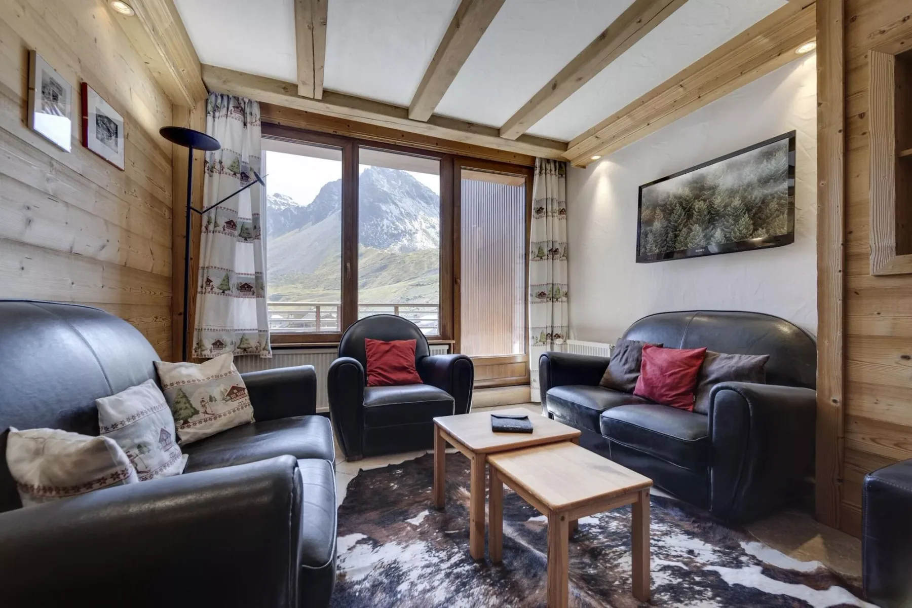 A living room with dark seating and a mountain view through the windows.