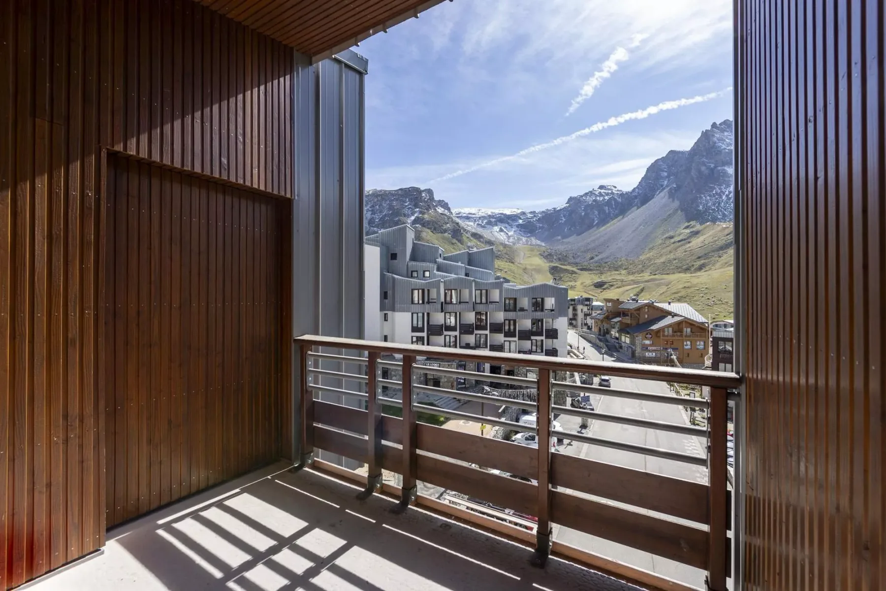 A balcony overlooks mountain scenery and nearby buildings.