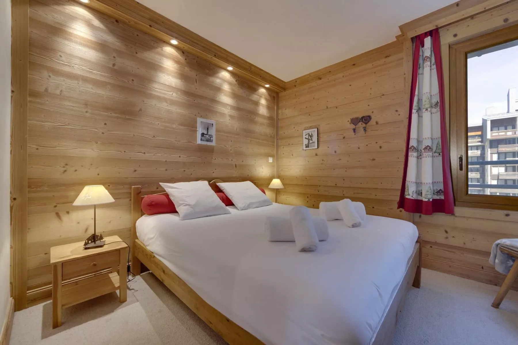 A bedroom with a large bed, bedside tables, and wood-paneled walls.