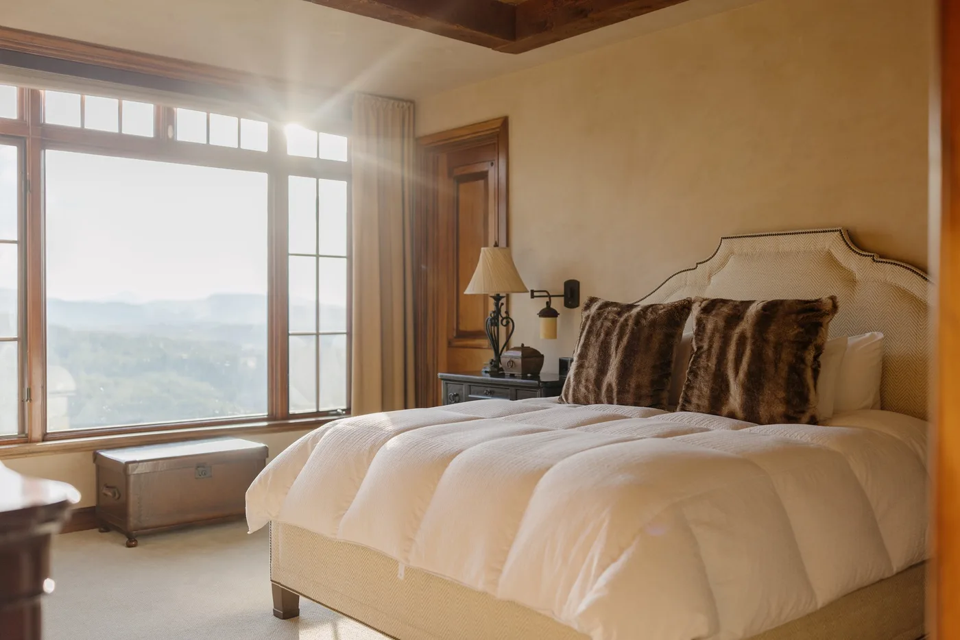 Un dormitorio con una cama grande junto a una amplia ventana con vistas a un paisaje montañoso.
