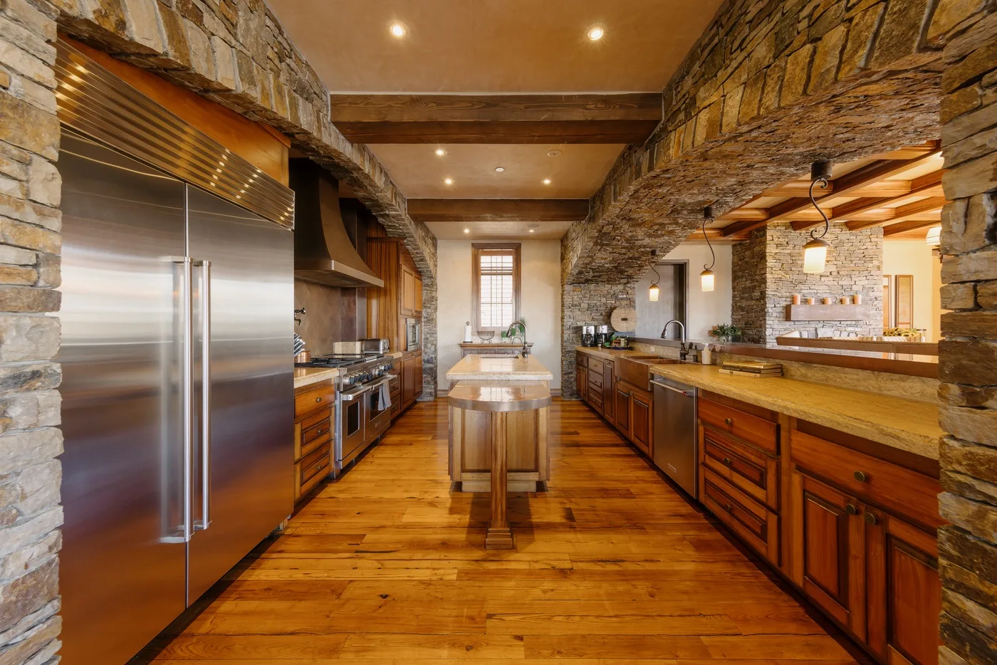 Una cocina amplia con gabinetes de madera, paredes de piedra y una isla central.
