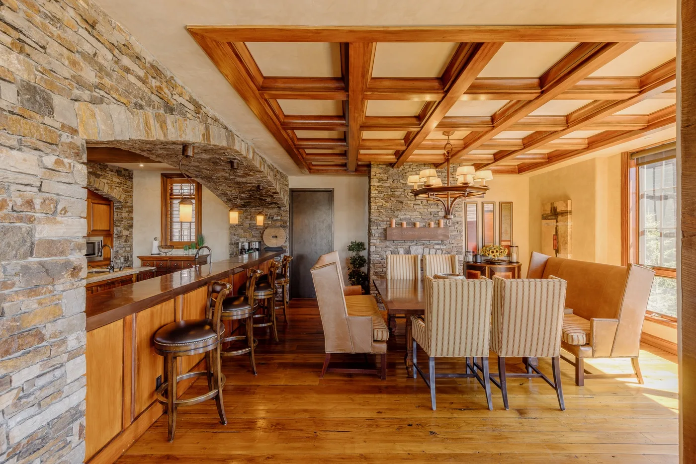 A dining area with a long table and chairs beneath a wood-beamed ceiling.
