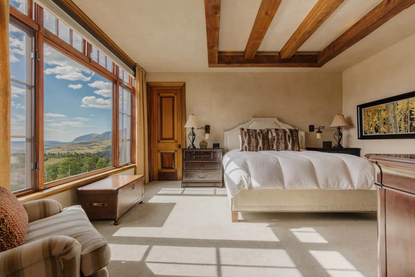 Un dormitorio con una cama junto a grandes ventanas con vistas al paisaje.