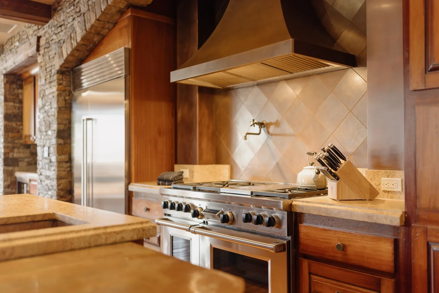 A kitchen with a stainless steel range beneath a large vent hood.