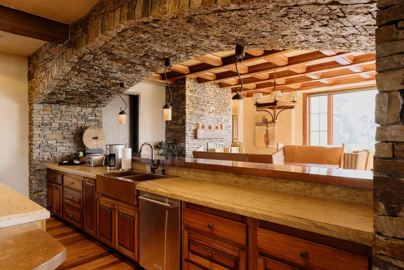 A rustic kitchen with a long wooden counter beneath exposed timber beams.