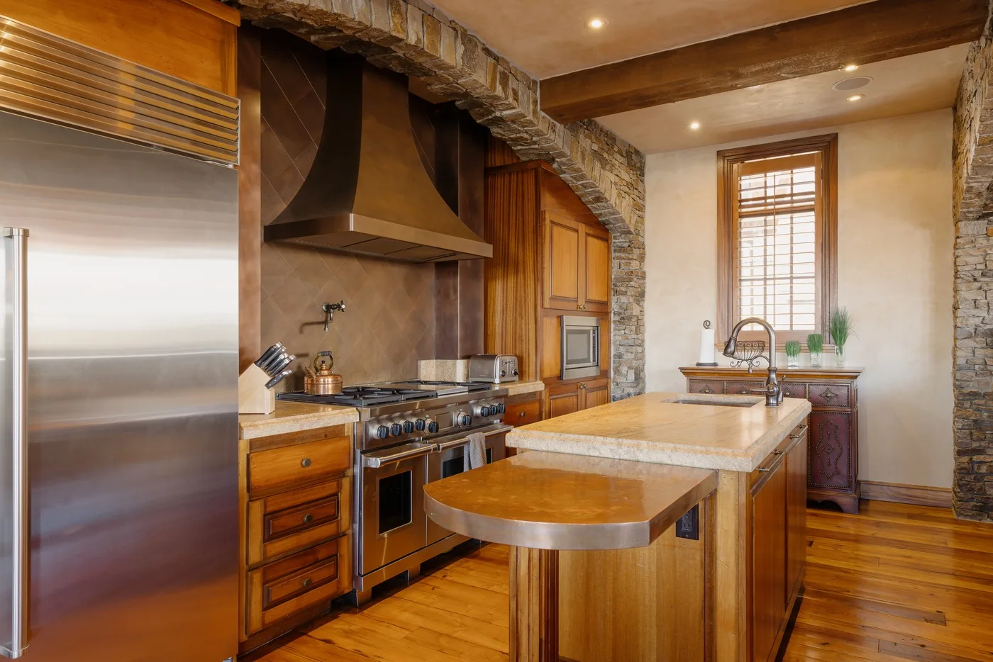 Una cocina cálida con gabinetes de madera, electrodomésticos de acero inoxidable y una isla central.