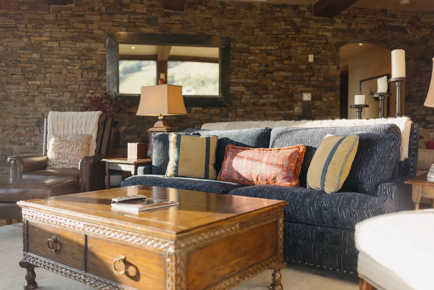 A living room with a dark sofa, colorful cushions, and a wooden coffee table.