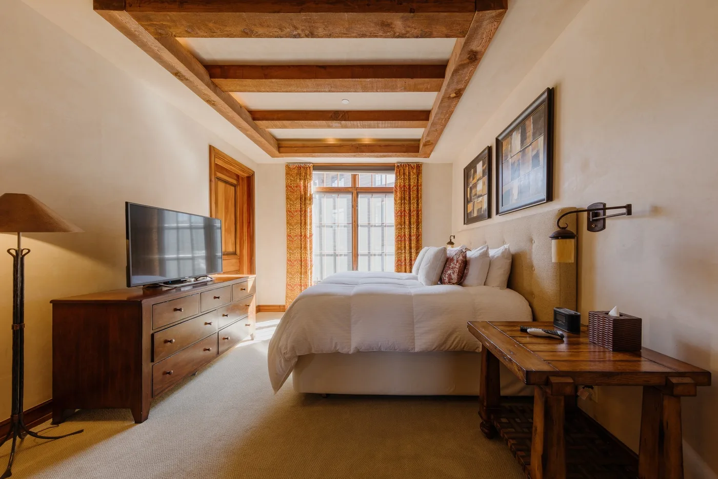 Un dormitorio con cama, cómoda de madera y una ventana grande.