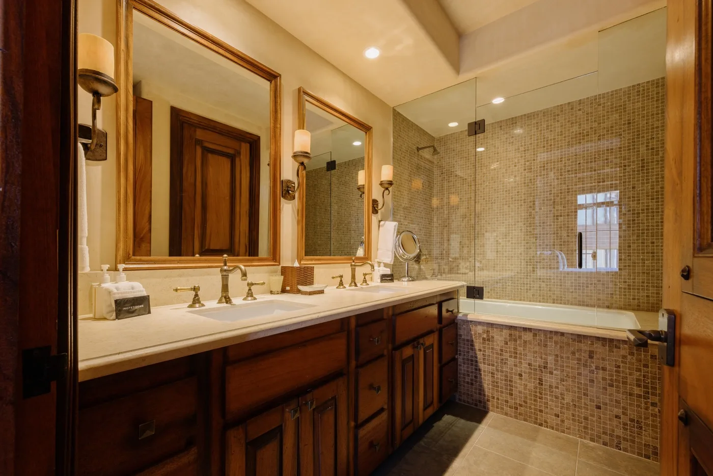 A bathroom with a long vanity, mirrors, and a tiled bathtub area.