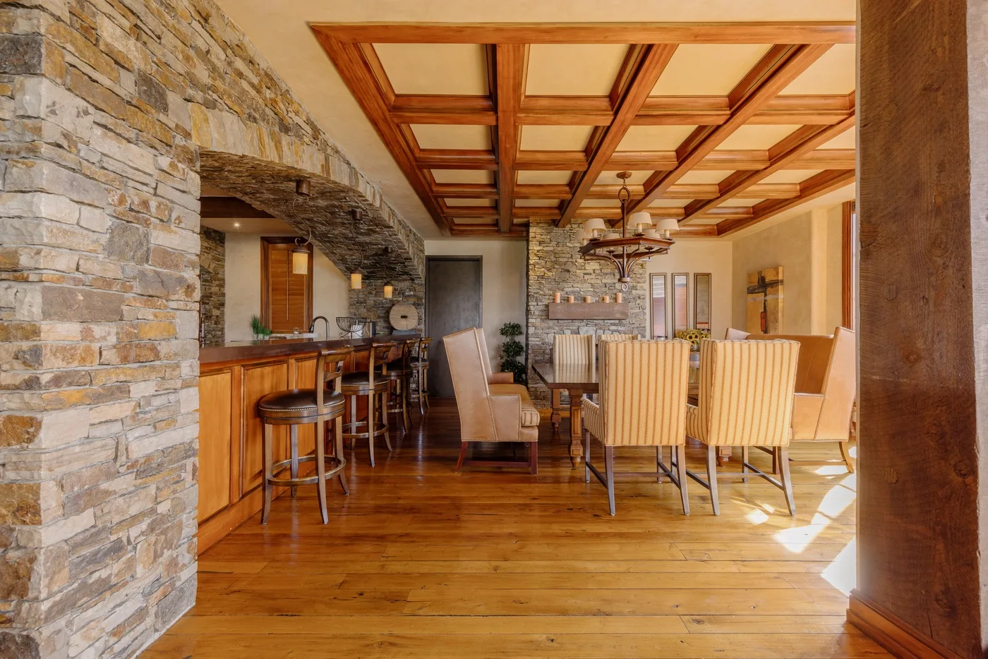 A dining area with a long wooden table beneath exposed ceiling beams.