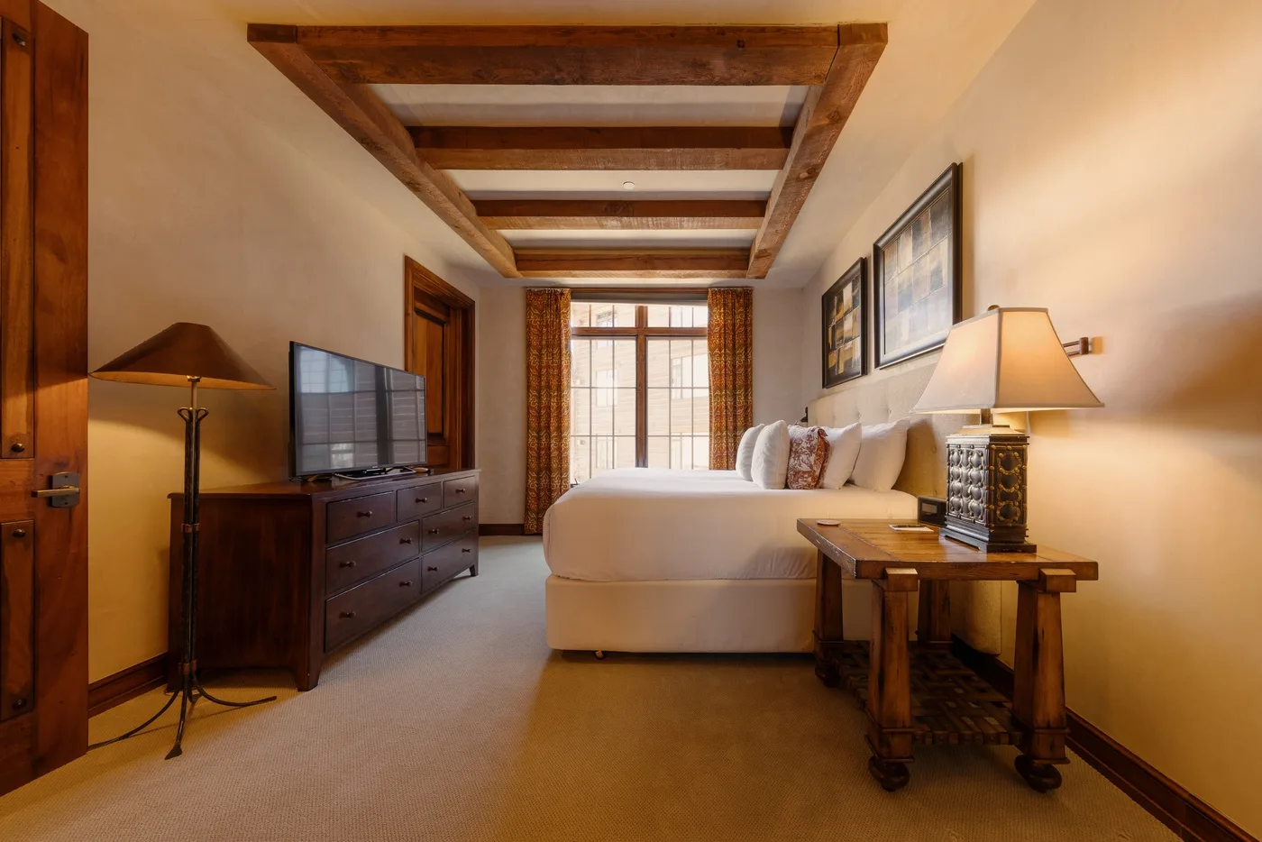 Un dormitorio con cama, televisor y vigas de madera en el techo.