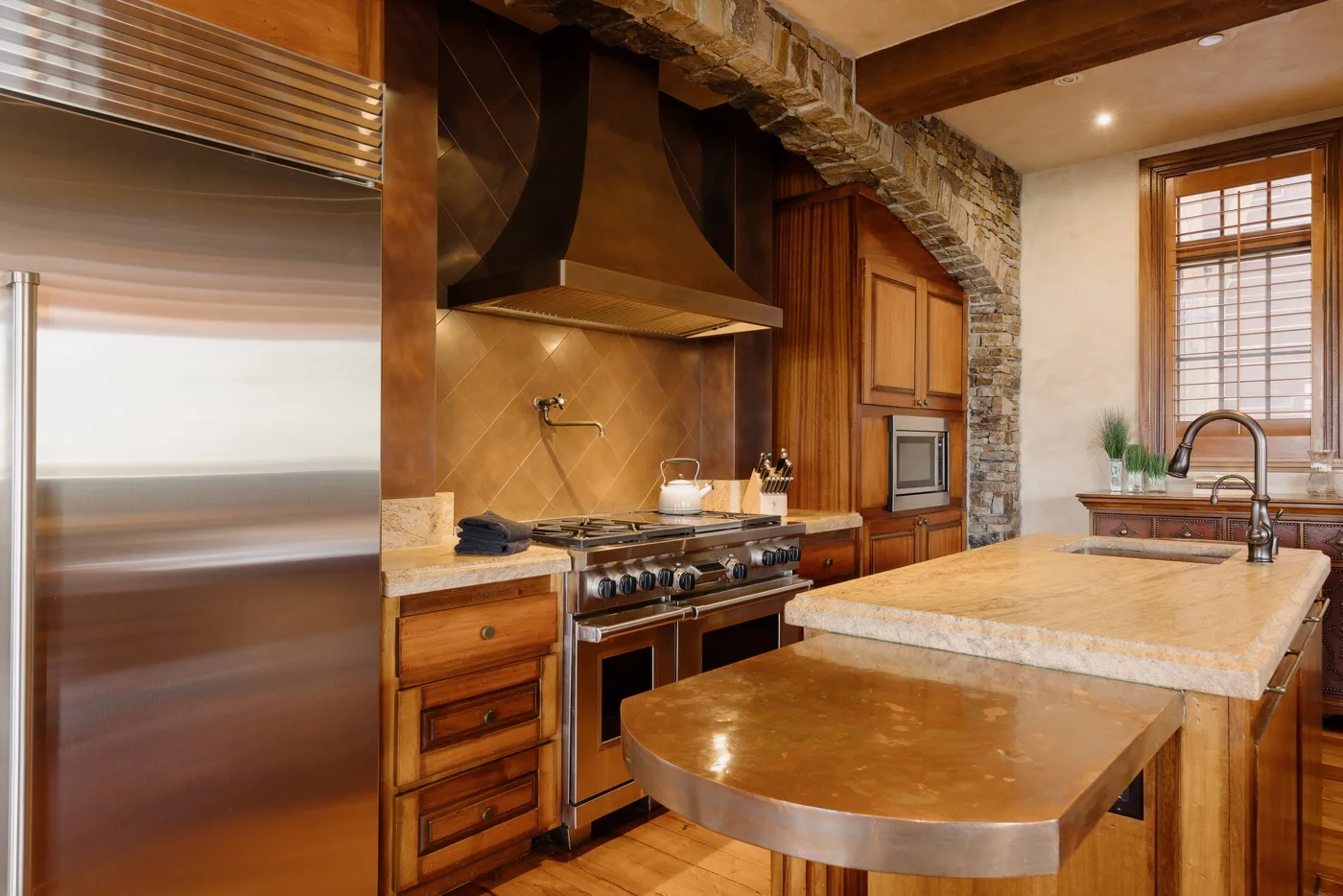 Una cocina revestida de madera con una isla central grande y electrodomésticos de acero inoxidable.
