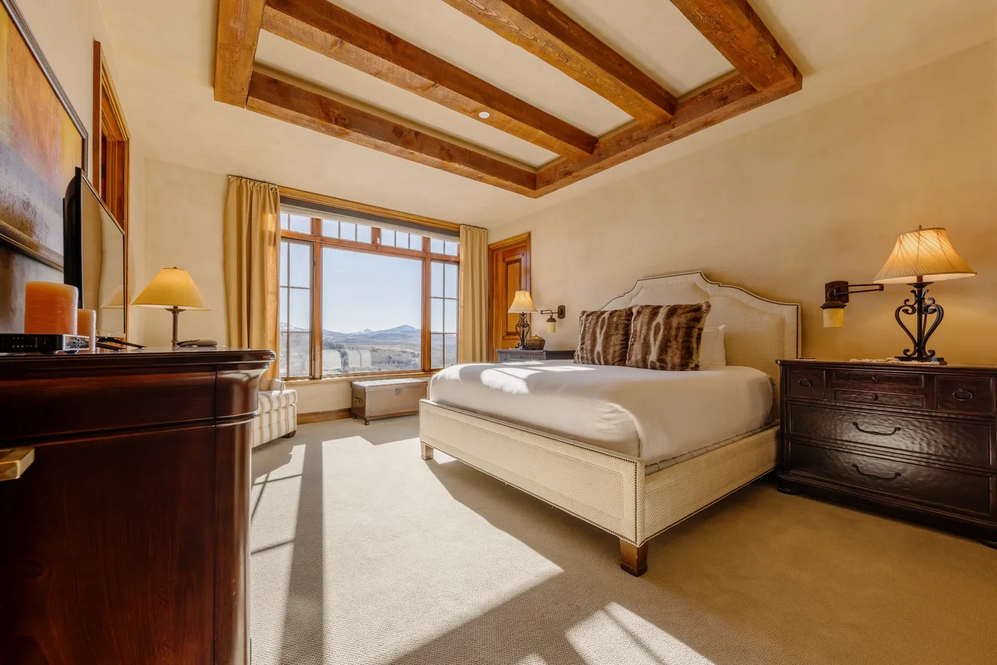 Un dormitorio con una cama grande, muebles de madera oscura y una ventana soleada.