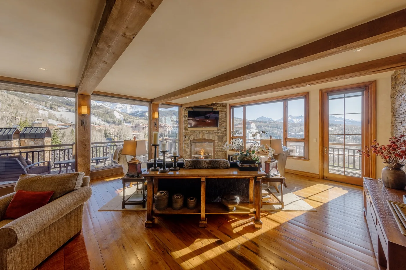 Una luminosa sala de estar con asientos, chimenea y grandes ventanales con vistas a las montañas.