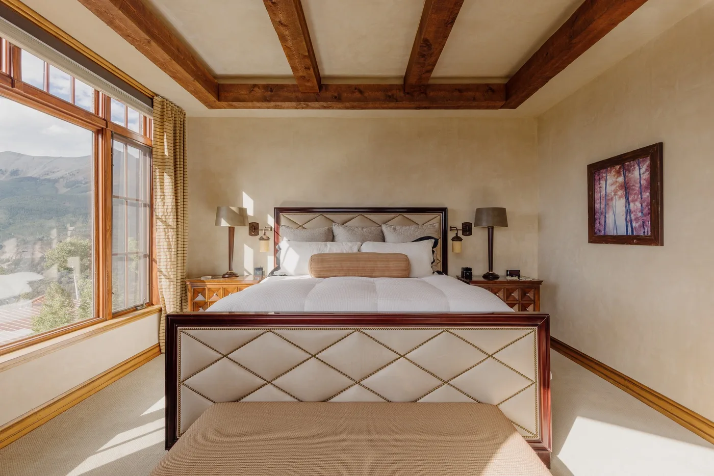 Un dormitorio con una cama grande, mesitas de noche y una ventana amplia con vistas al paisaje.