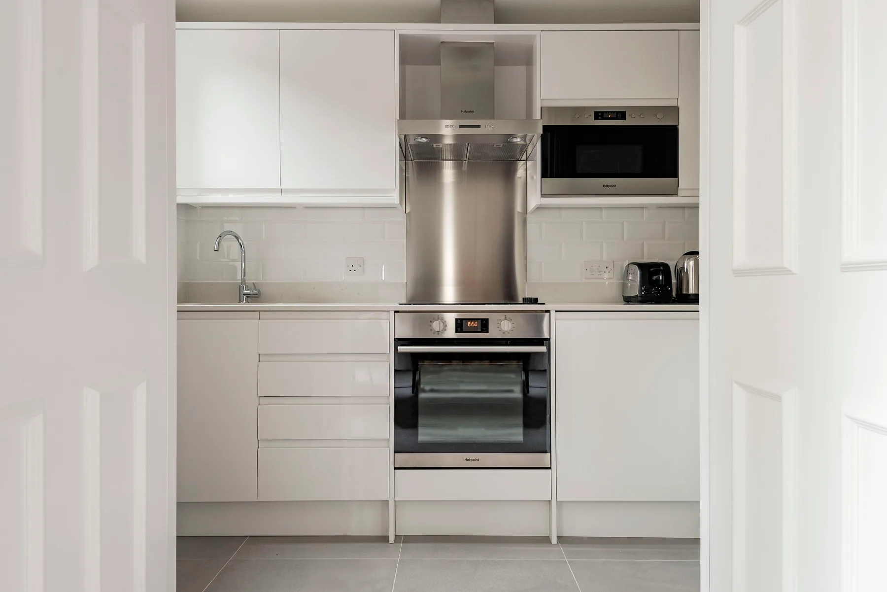 Una cocina luminosa con gabinetes blancos, horno y microondas.