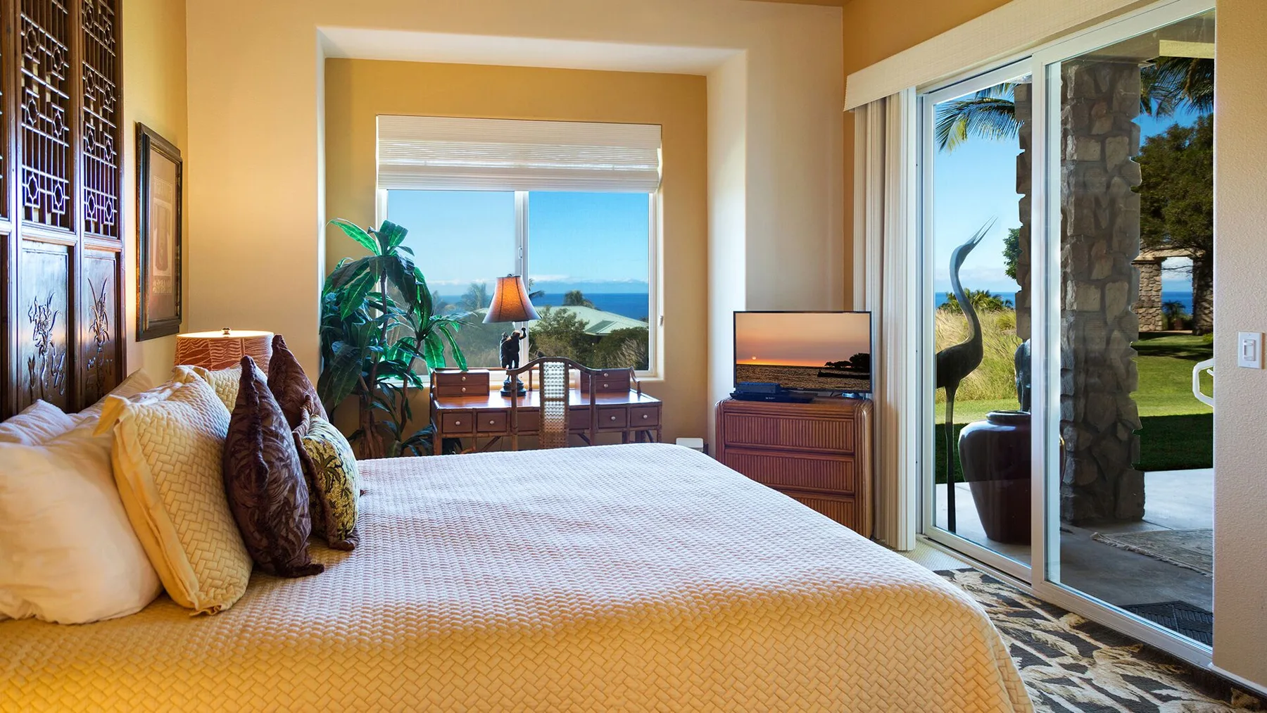 A bedroom with a bed, a window overlooking the water, and sliding glass doors.