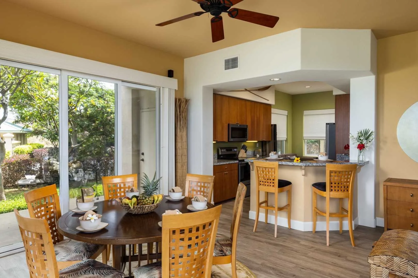 A dining area opens onto a kitchen, with sliding glass doors overlooking greenery.