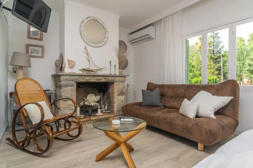 A living room with a brown sofa, a fireplace, and a glass coffee table.