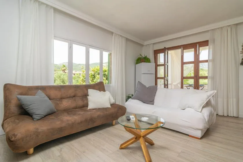 A bright living room with brown and white seating beside large windows.