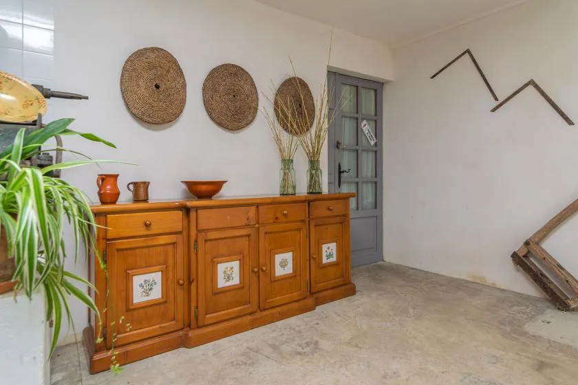 A hallway with a wooden sideboard, decorative baskets, and a gray door.