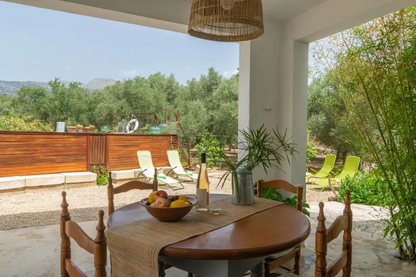 A covered outdoor dining area overlooks a wooden deck and surrounding greenery.