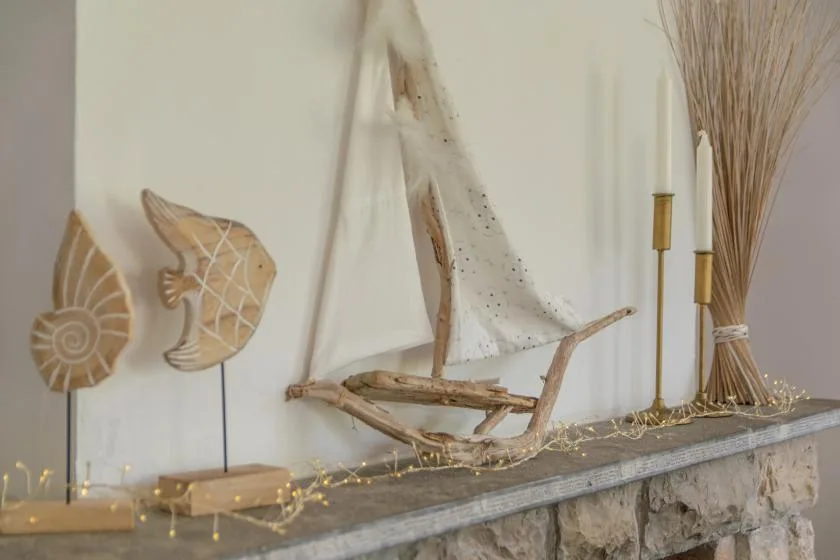 A decorative shelf display features driftwood ornaments, dried grasses, and string lights.