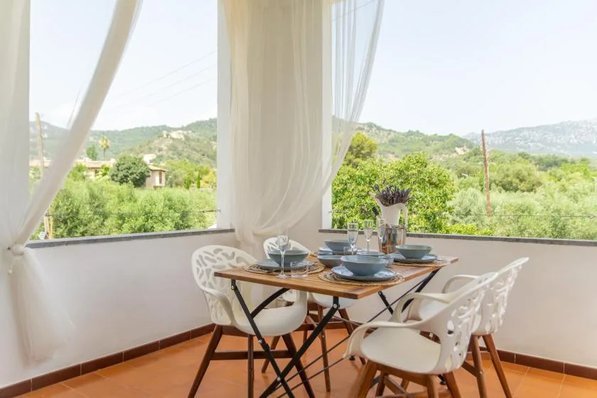 A dining area by large windows overlooks a green hillside.