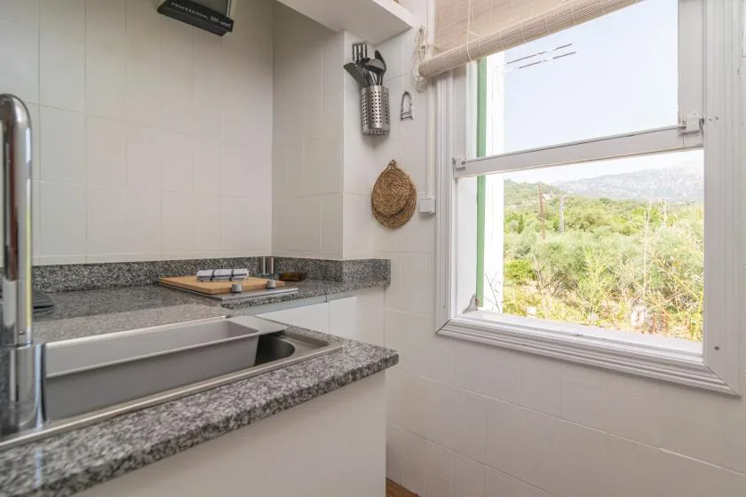 A bathroom vanity with a sink sits beside a large window overlooking greenery.